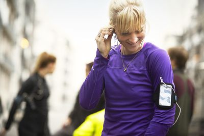Skupina běžců připravuje v městském prostředí, sportovec připojením sluchátek
