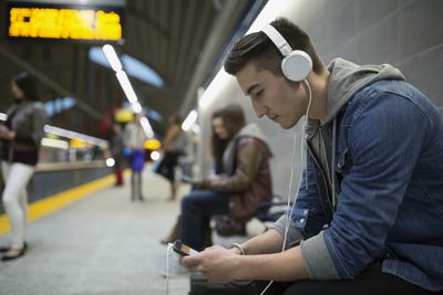 Obrázek osoby, která poslouchá podcast při čekání na vlak