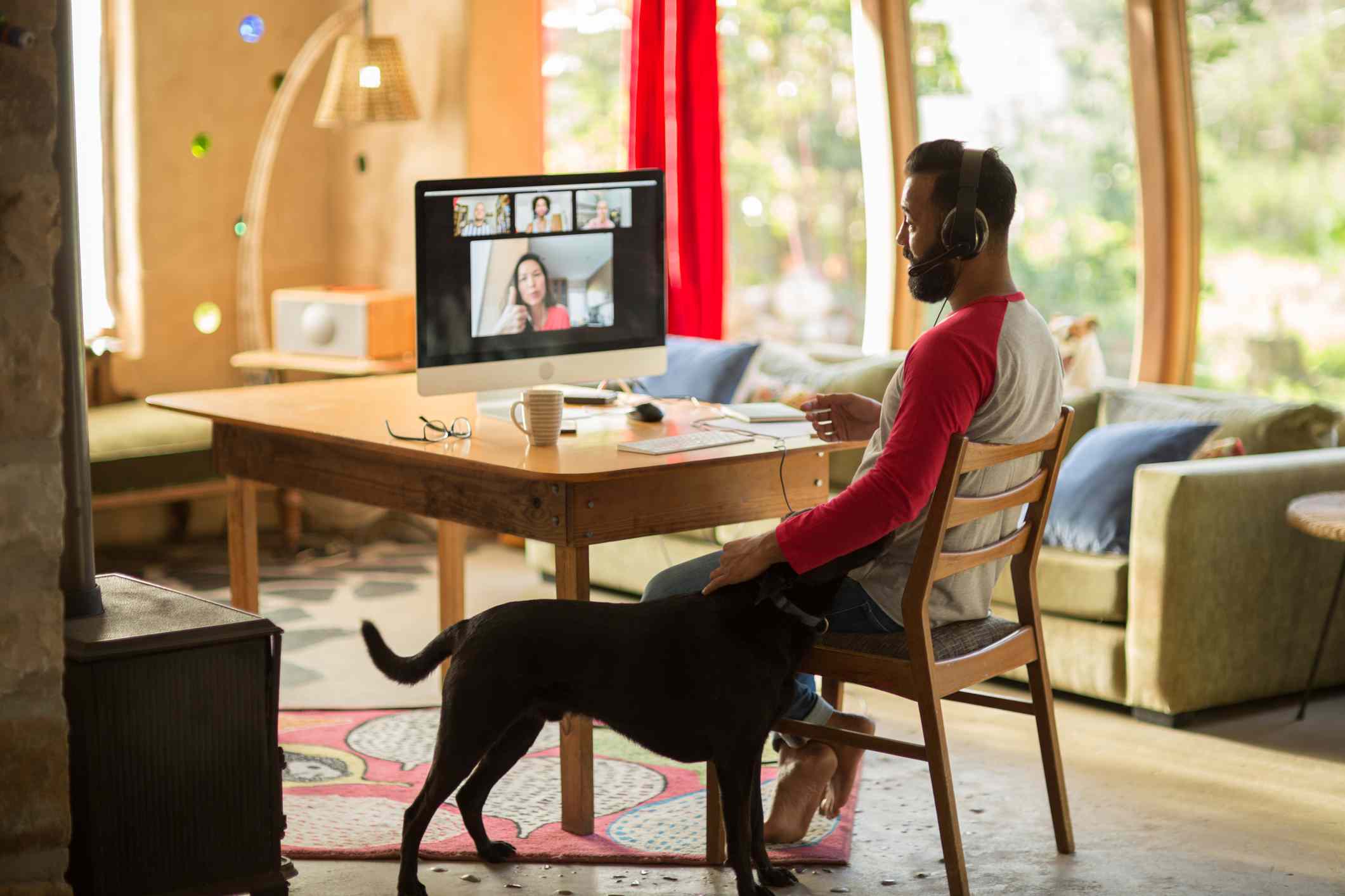 Muži, kteří pracují z domova na svém počítači a mazlení svého psa během uzamčení