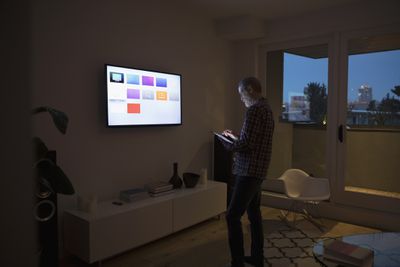 muž ovládající Apple TV s iPadem