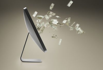 Osobní počítač a plovoucí dolarové bankovky vycházející z obrazovky