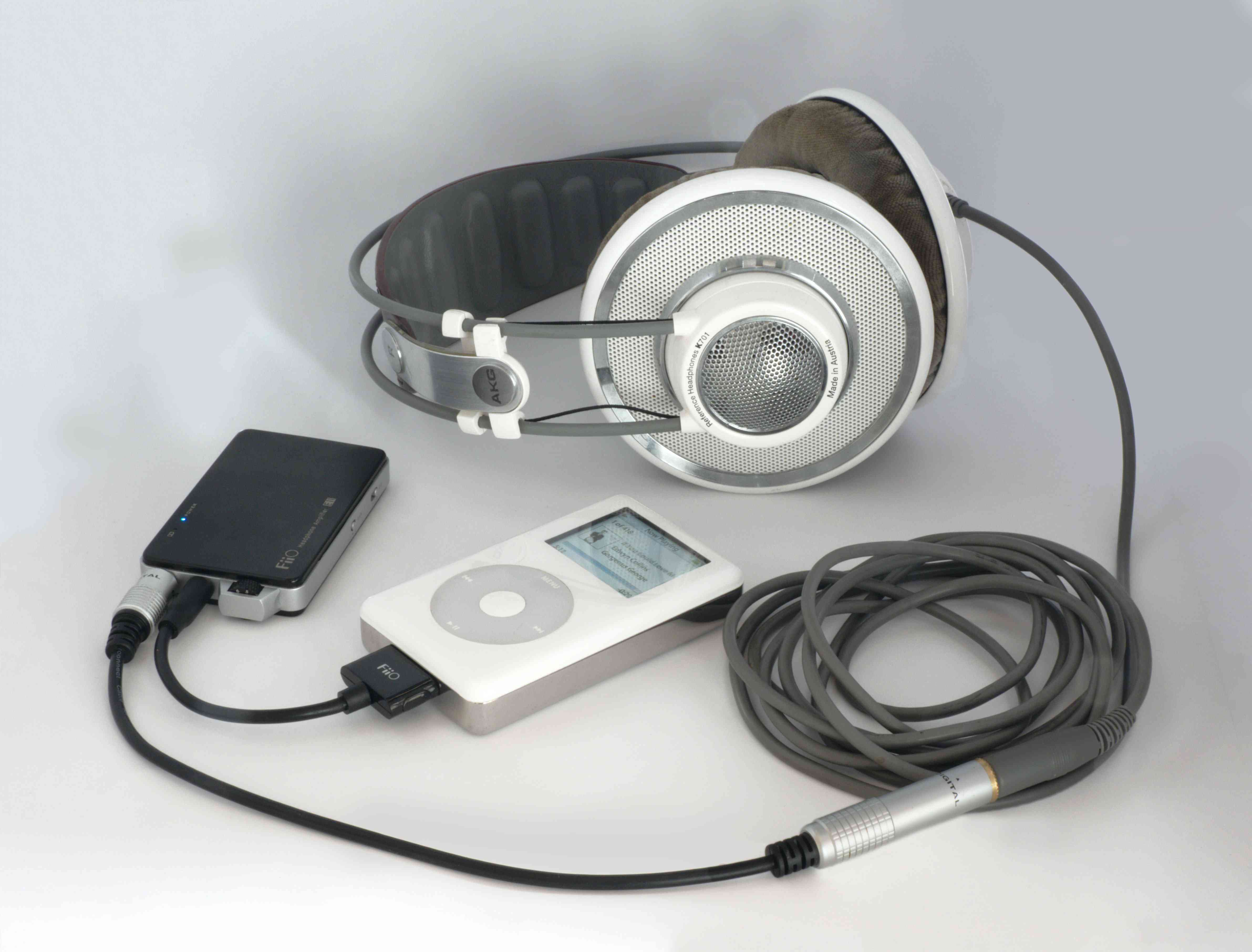 Stříbrná a bílá sluchátka se připojují k DAC připojenému k Apple iPod. 