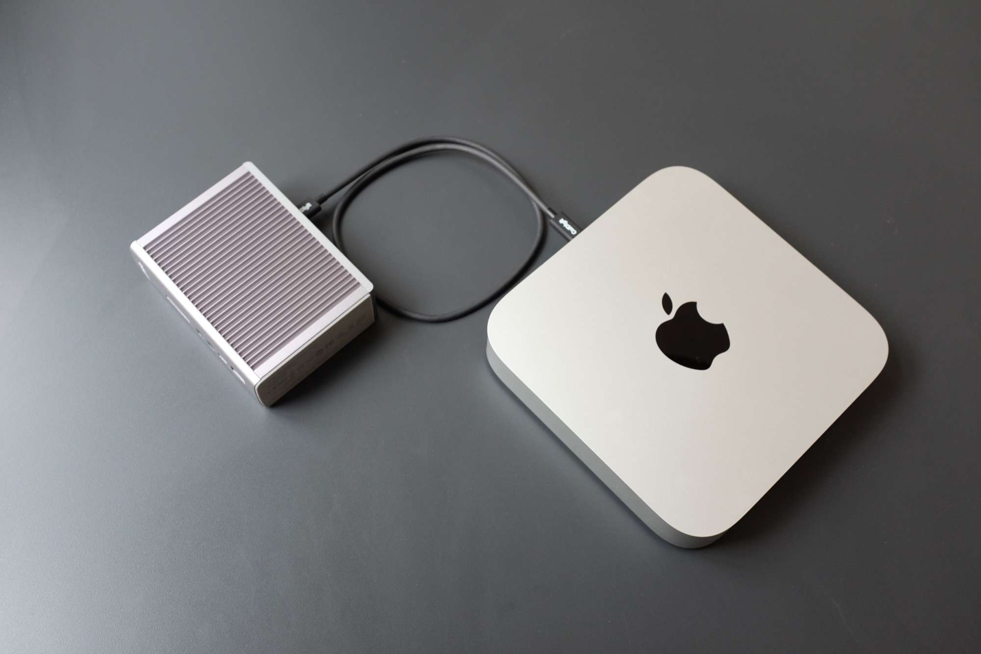 CalDigit TS3 + připojený k Mac Mini a položený na šedém stole