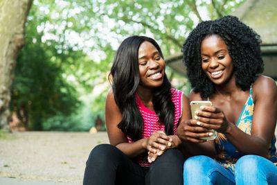 Dvě ženy se smějí a dívají se na iPhone