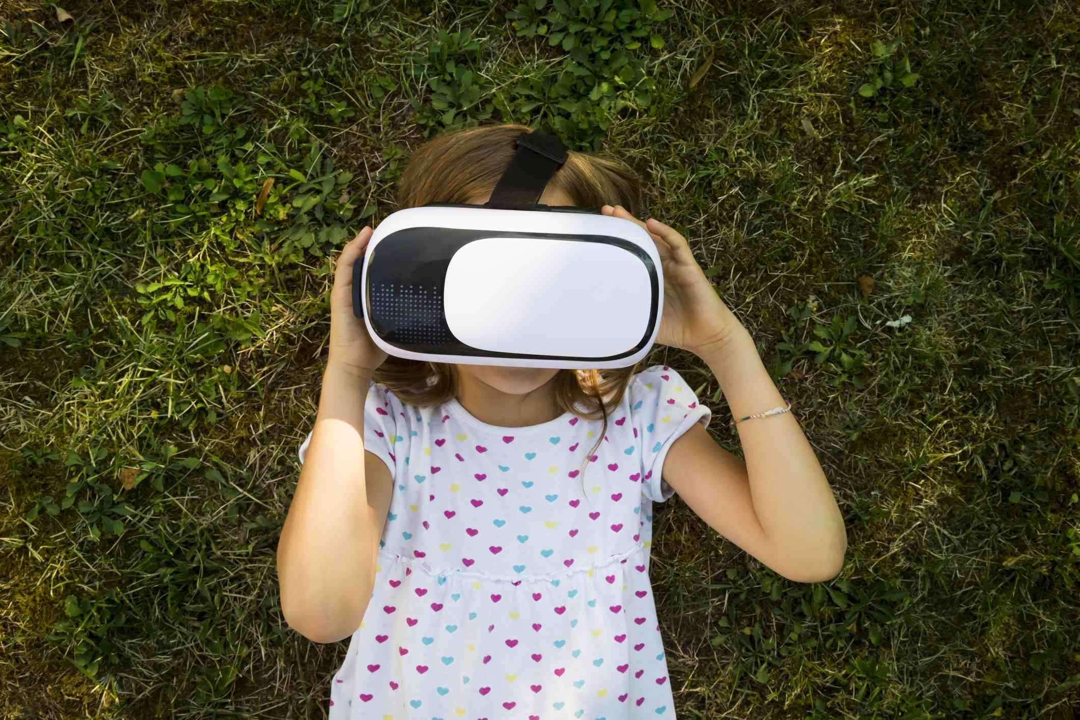 Dítě nosit brýle VR ležící na zemi v zahradě. 