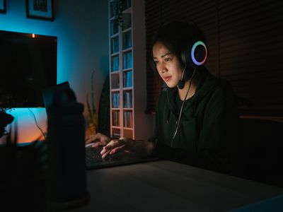Žena sedí ve tmě nosit sluchátka s notebookem před sebou