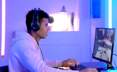 Muž streamující videohry na Twitch na svém počítači s fialovými světly kolem sebe.