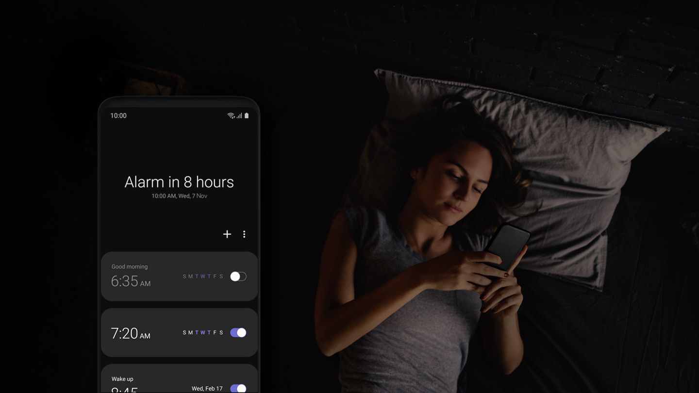 Žena v posteli pomocí svého telefonu, rozhraní alarmu z jednoho uživatelského rozhraní umístěné vlevo