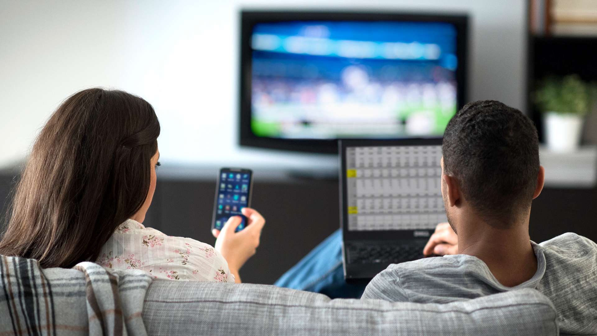 Mužské a ženské vysokoškoláky streamující média z iPhonu a notebooku do televize na koleji