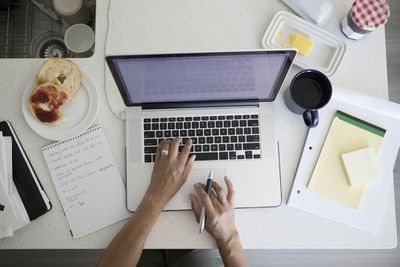 Zpětný pohled žena pracující na notebooku na snídani kuchyňské lince