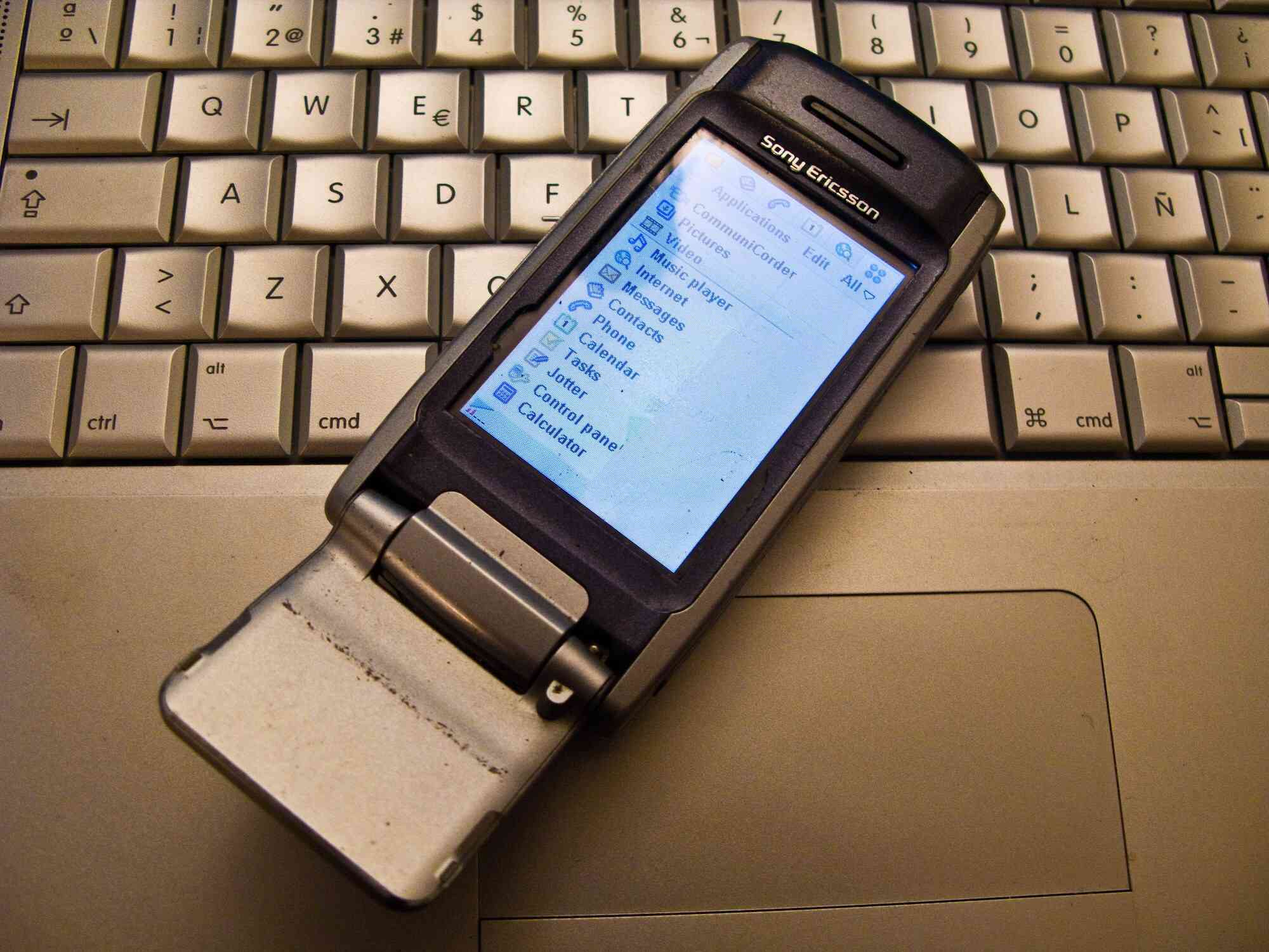 Fotografie starého mobilního telefonu Sony Ericsson položeného na notebooku