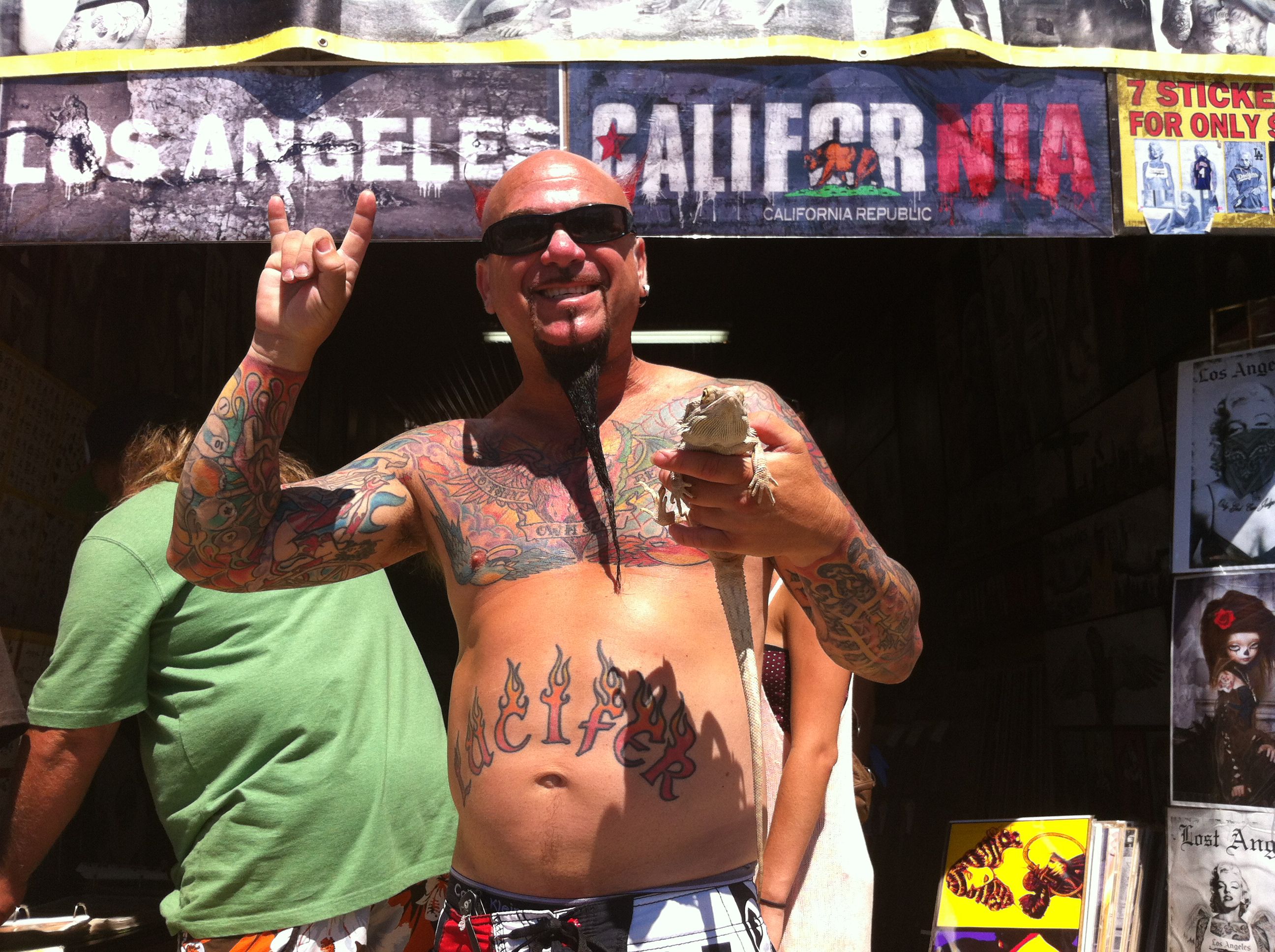 Tetovaný muž před LA banner drží ještěrku