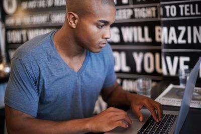 Mladý muž pomocí přenosného počítače v kavárně
