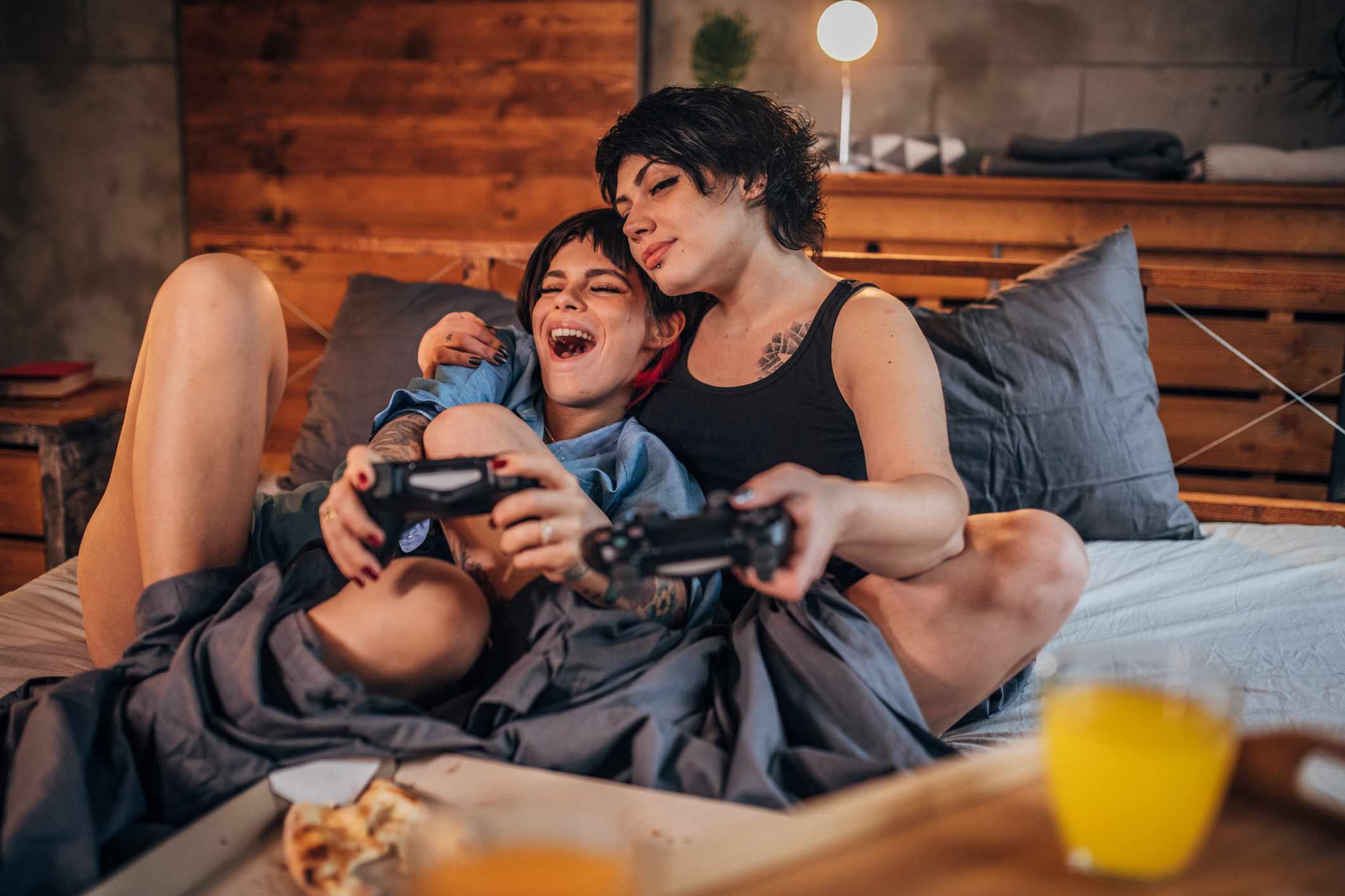 Pár hraní videoher v ložnici při jídle pizzy. 