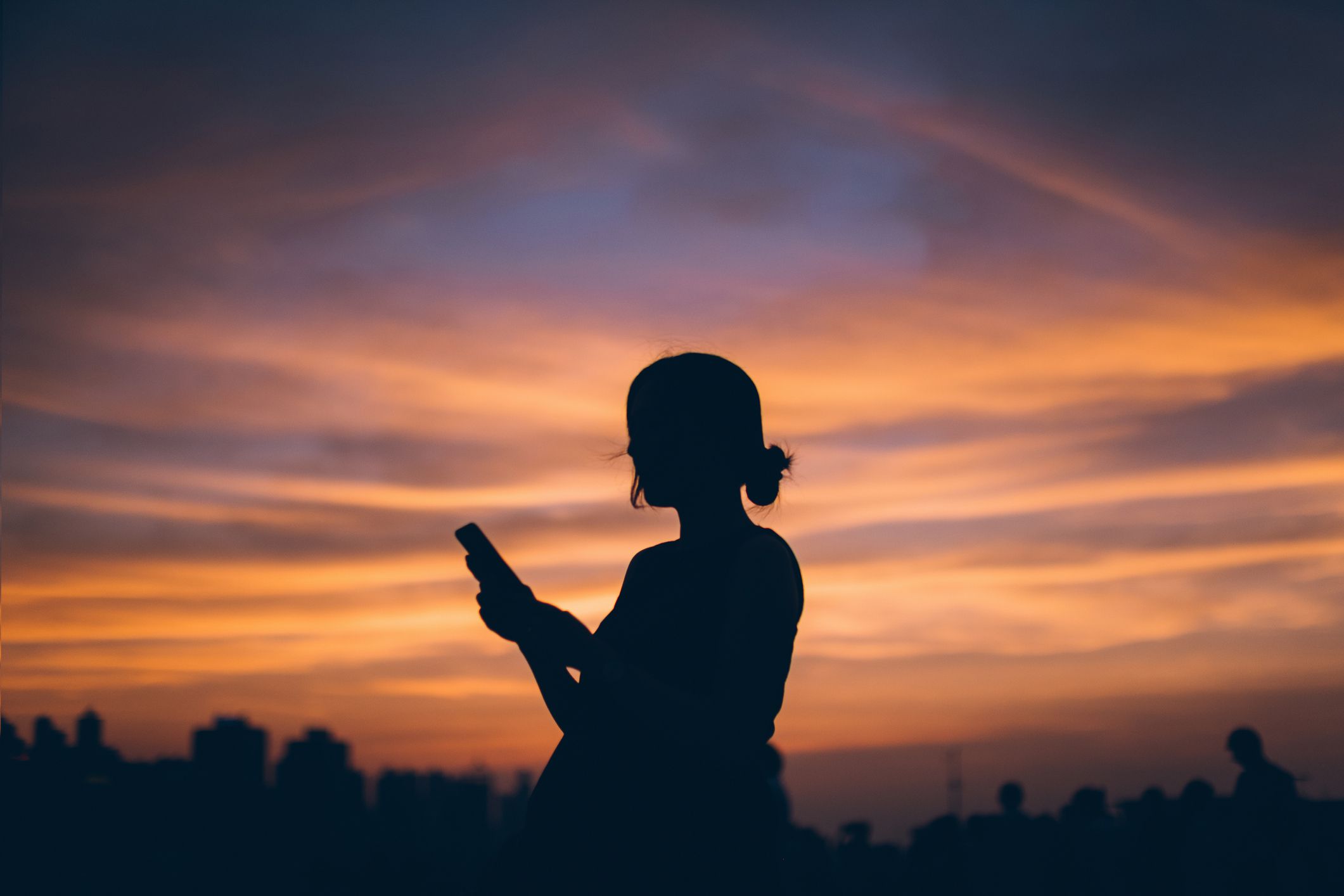 Žena na telefonu siluetu při západu slunce