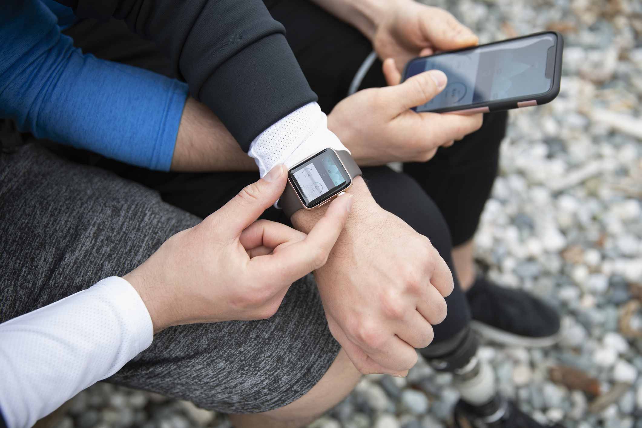 Pár běžců při pohledu na hodinky Apple a iPhone