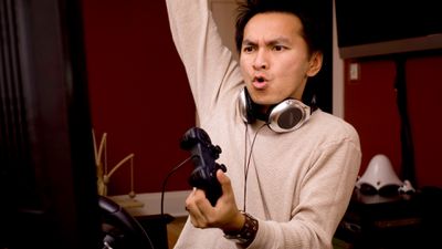 Asiat hraje videohry na počítači se sluchátky na krku