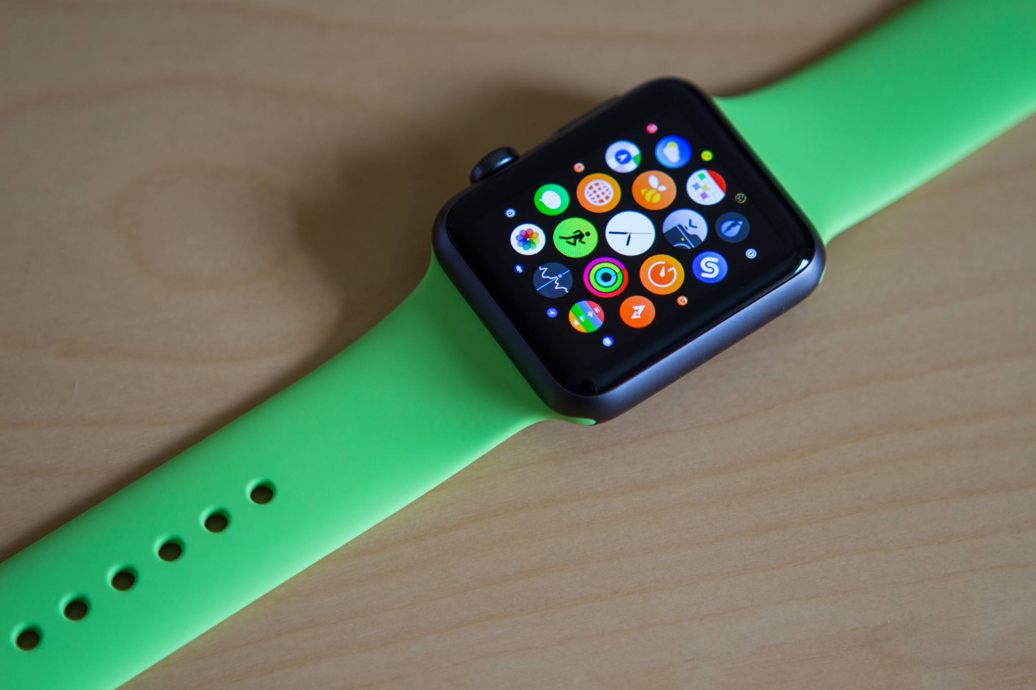 Apple Watch se zeleným sportovním řemínkem na stole