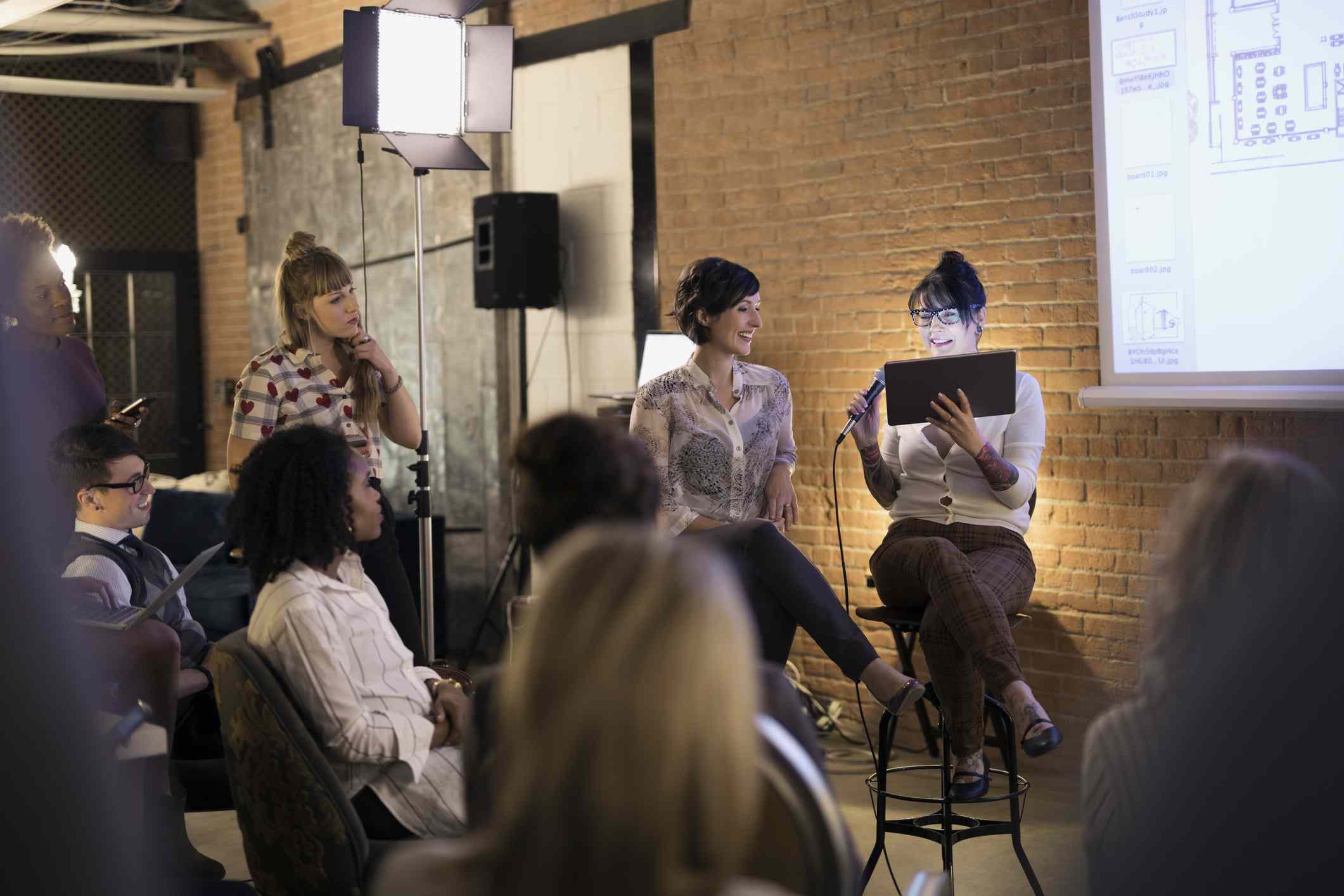 Návrhářky s mikrofonem a digitálním tabletem, vedoucí konferenčního setkání