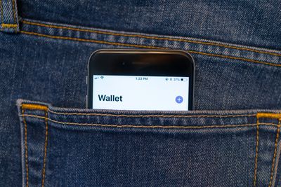 Aplikace Apple Wallet na iPhonu trčící z kapsy džínů