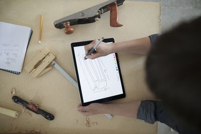Tesař, skicování s digitálním tabletovým perem na pracovním stole v dílně