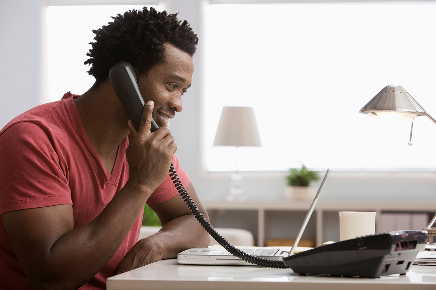 Usmívající se černoch mluví po telefonu v domácí kanceláři