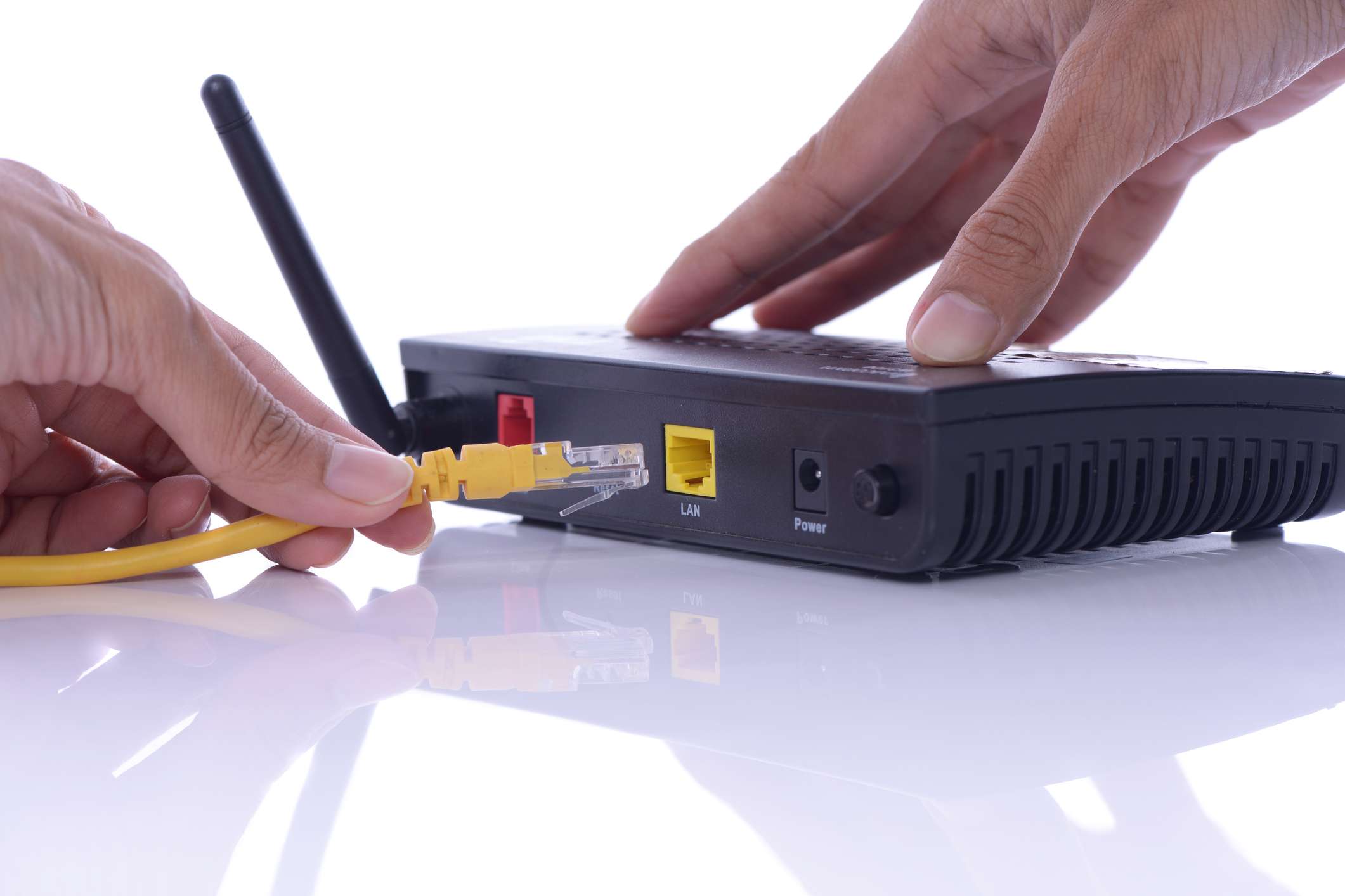 Osoba připojující ethernetový kabel k bezdrátovému routeru