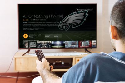 Muž sleduje sport Amazon Prime ve své televizi.
