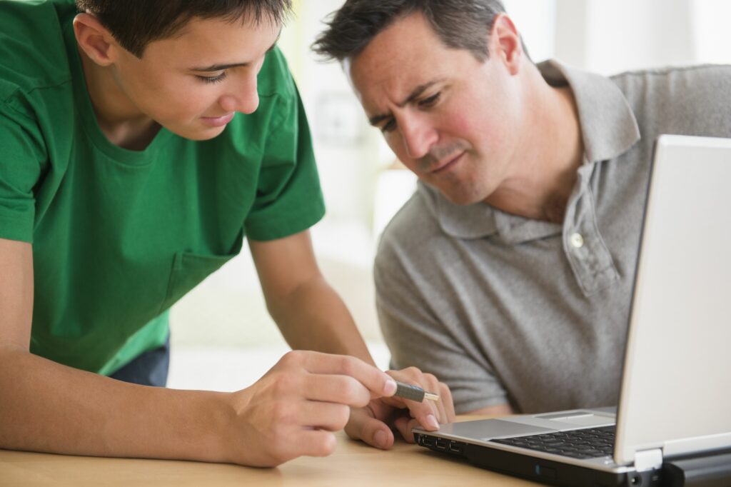 caucasian son showing father how to use usb stick in laptop 482143309 5b78d1a646e0fb002ce0da43