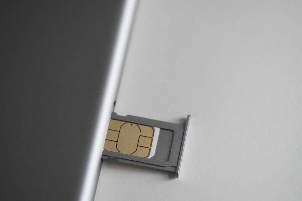 close up of sim card and mobile phone on white table 743692241 5c4cc359c9e77c0001f321e7