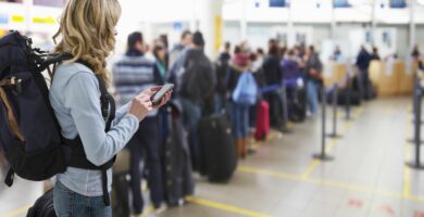 female traveller texting at airport check in desk 142309131 5a0b352813f1290037c17caf