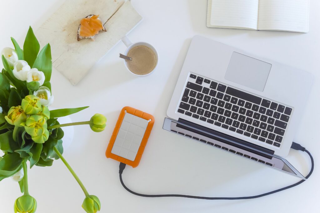 home office high angle view or directly above view of laptop with external hard disk drive and flower vase on white table 637423280 5b0424891d640400361162ba