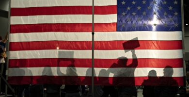 people silhouetted against an american flag 1214707683 405991a5634c4e6b976c66b0a1019a09