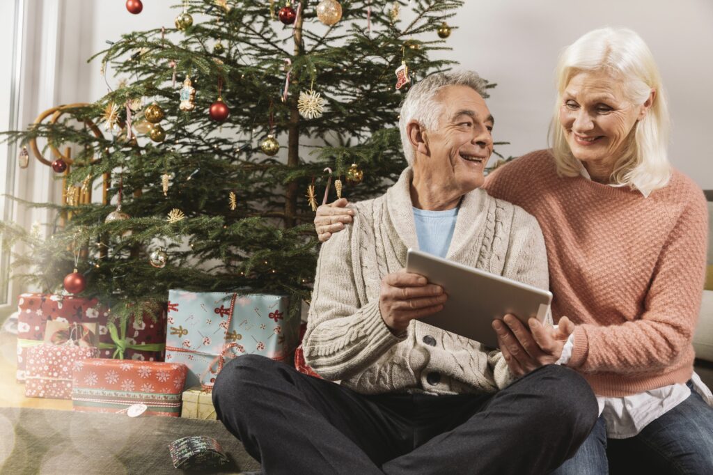 senior couple looking at a tablet computer in front of christmas tree 634464023 59c3e269aad52b00119bd3d8