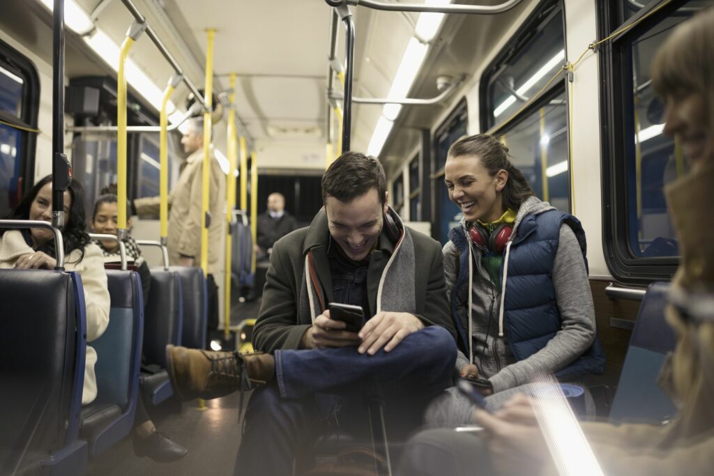 smiling young couple commuters texting with smart phone on bus 900897668 db9bb98059304e5b86181cd2beb3e7e4