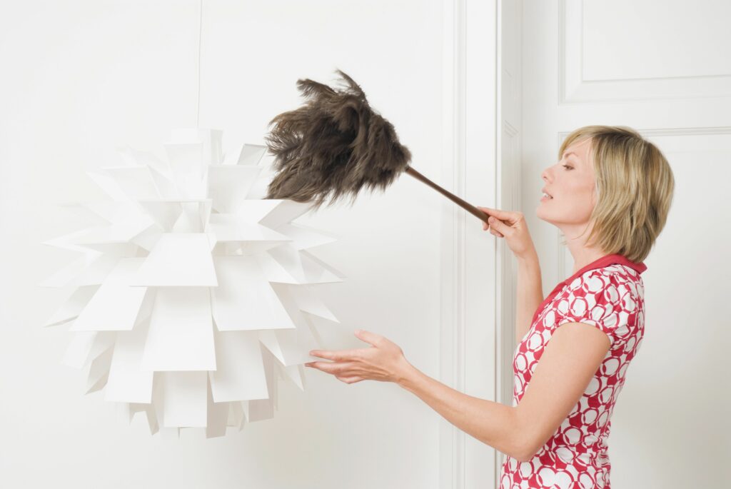 woman dusting a lamp with a feather duster 535256610 5b377454c9e77c001ae7dfcb