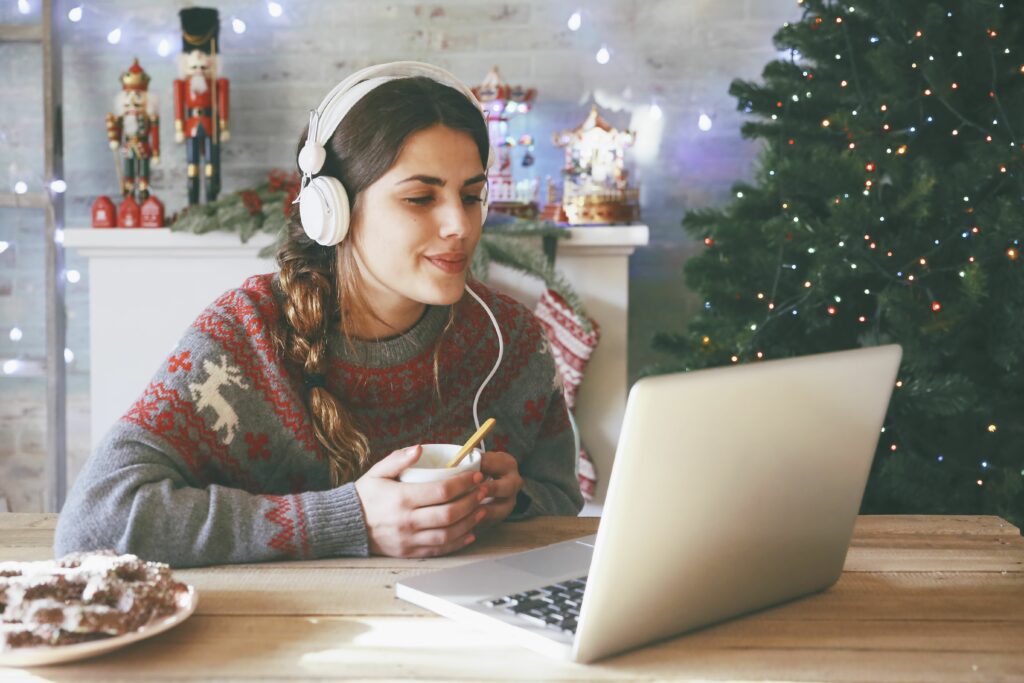 woman with cup of coffee using laptop and headphones at christmas time 681904577 59babded519de20010ea535e