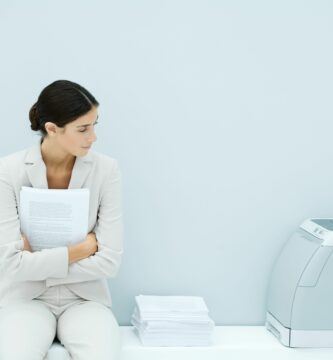 young woman in suit sitting next to printer 81737128 5b2afc9543a10300367c44f4