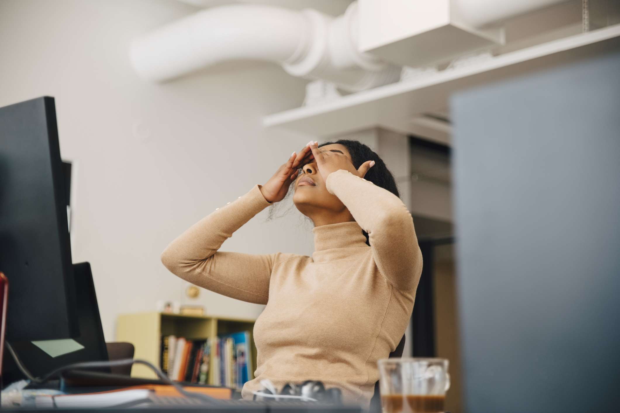 Frustrovaná žena počítačový programátor s hlavou v rukou sedí v kreativní kanceláři