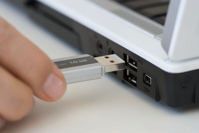 Osoba zapojující USB klíč do notebooku