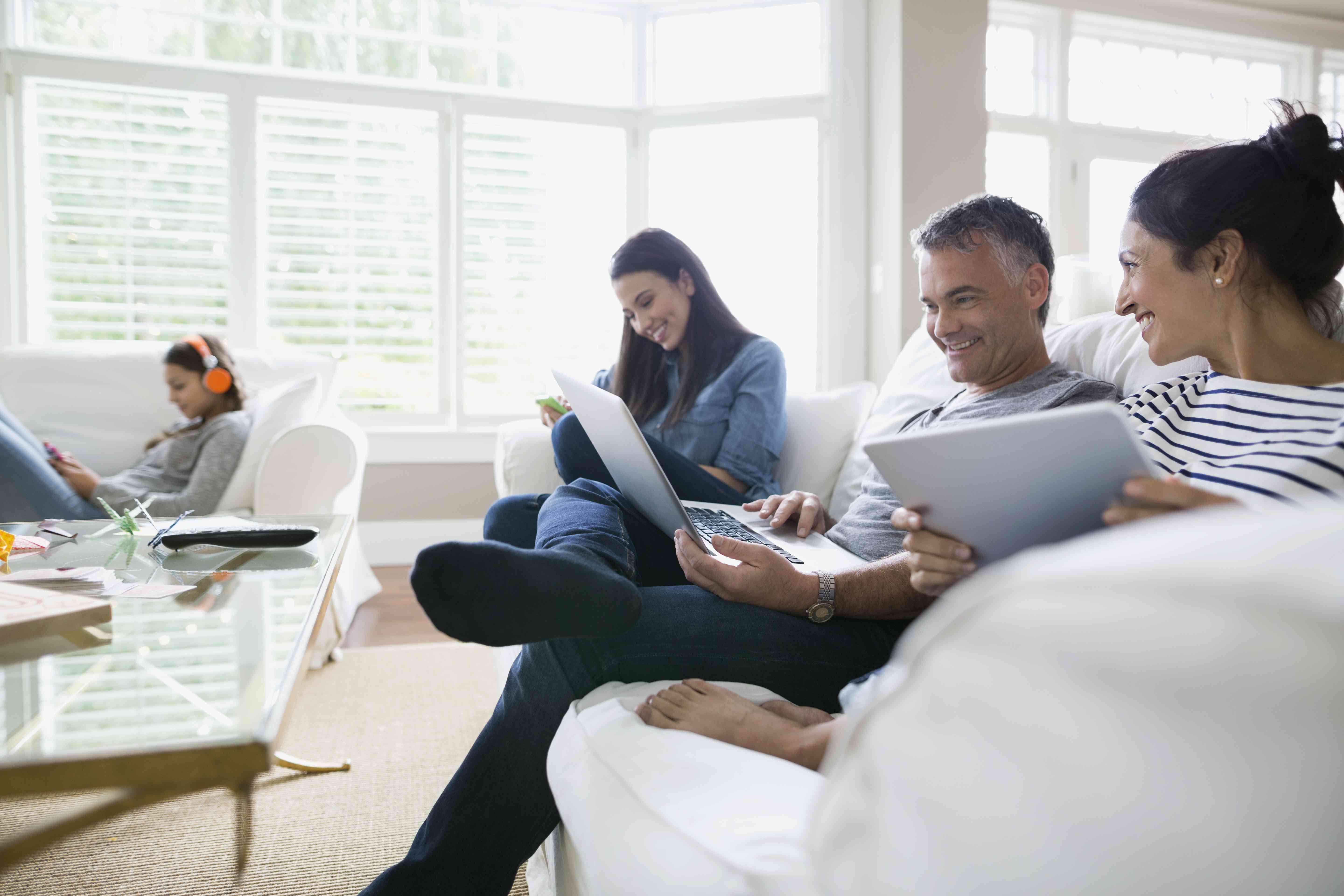 Rodina využívající bezdrátovou technologii na pohovce v obývacím pokoji