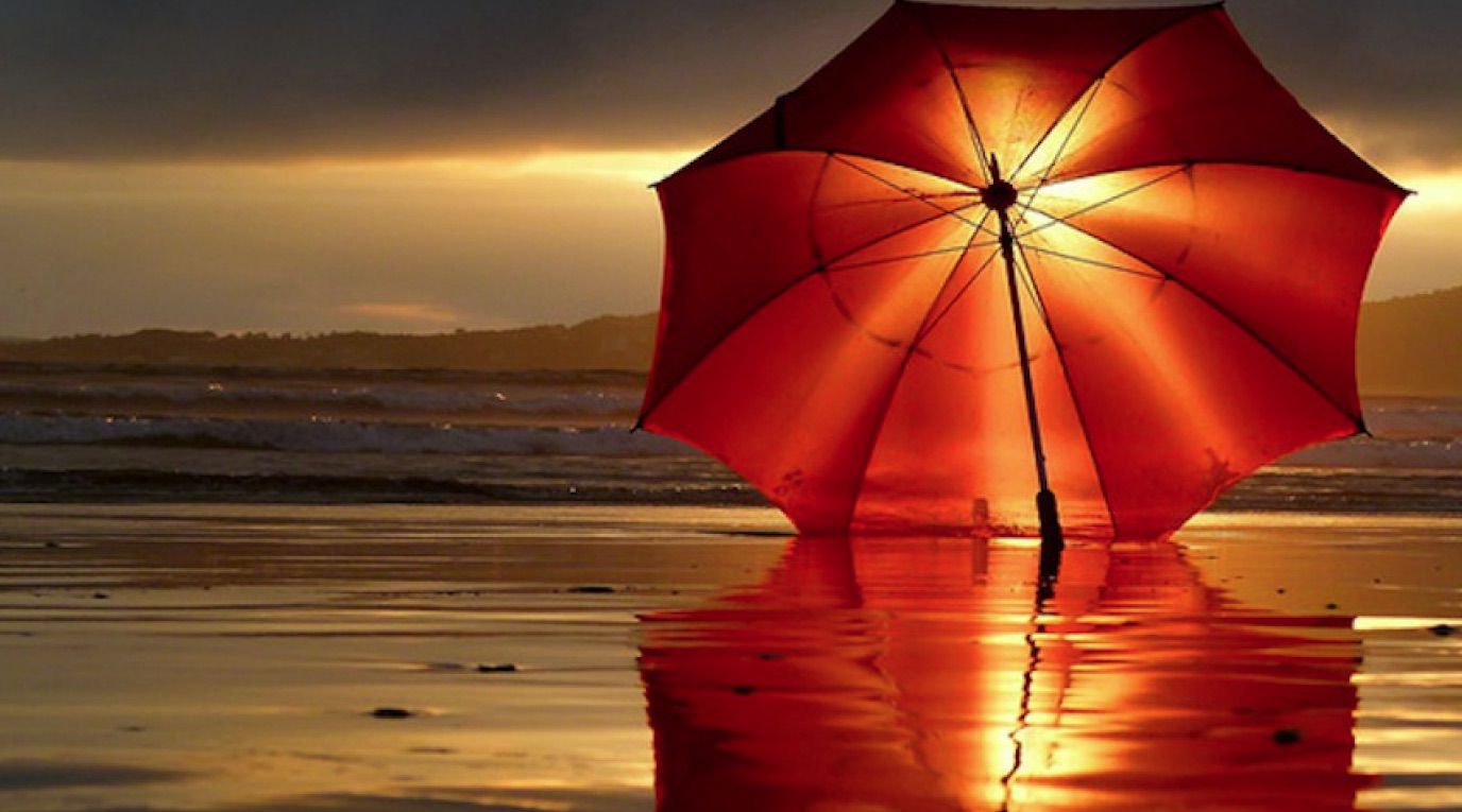 Zdarma plážová tapeta s červeným slunečníkem při západu slunce