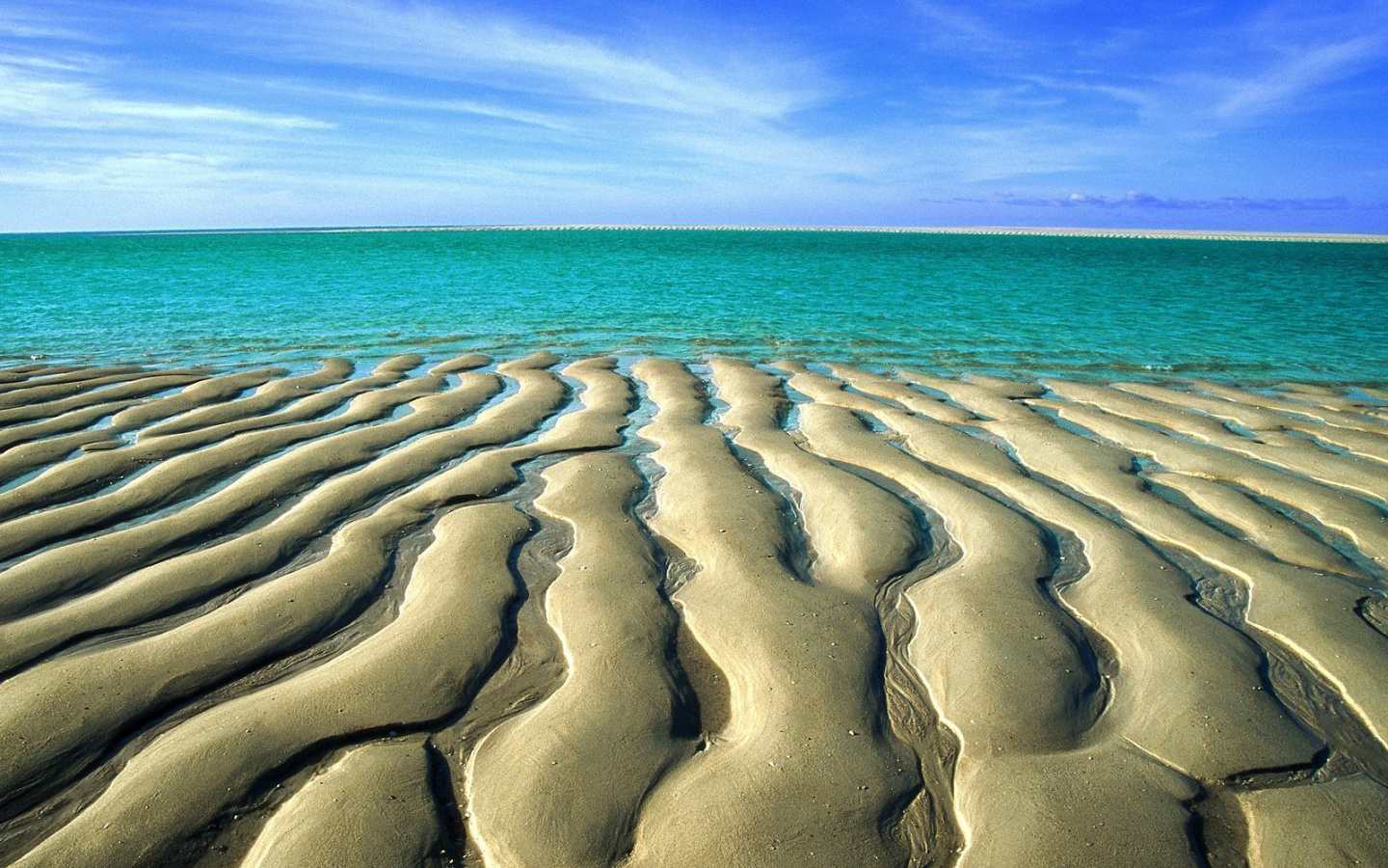 Zdarma tapeta na plochu s vlnkami v plážovém písku před vodou
