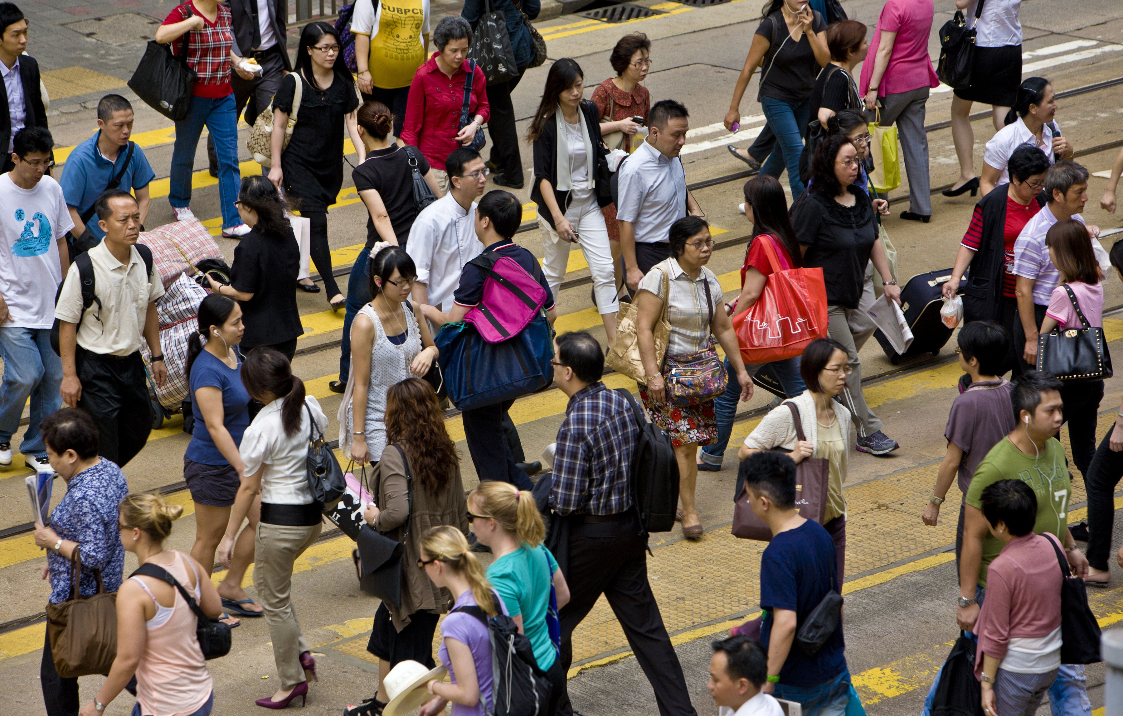 Obrázek davu lidí přecházejících ulici v čínském Hongkongu.