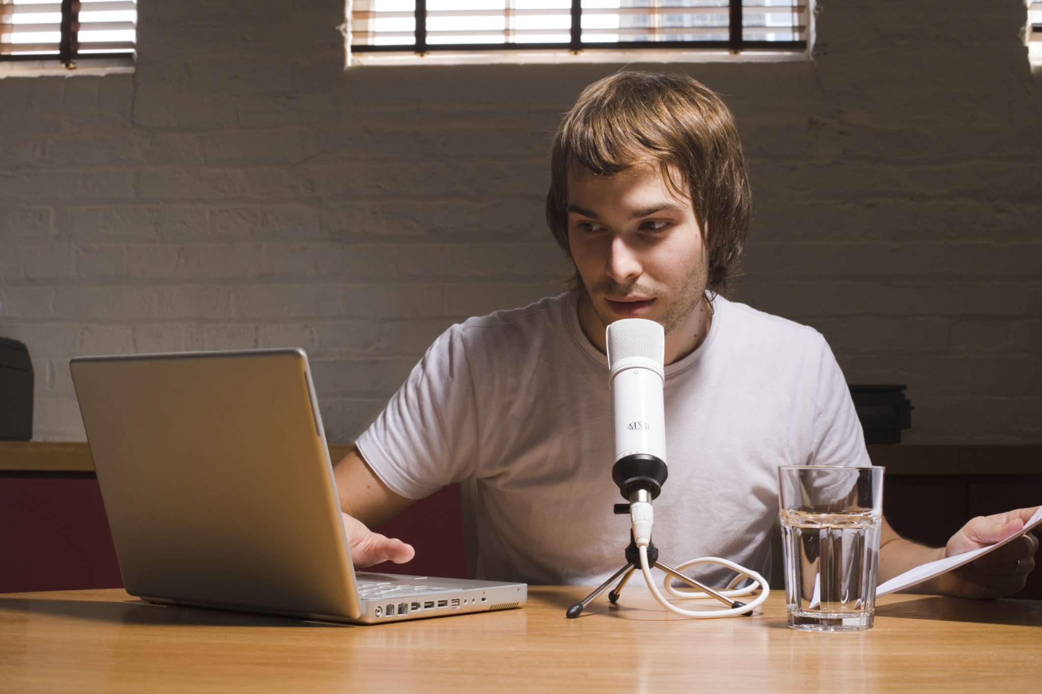 Muž podcasting s notebookem a mikrofonem