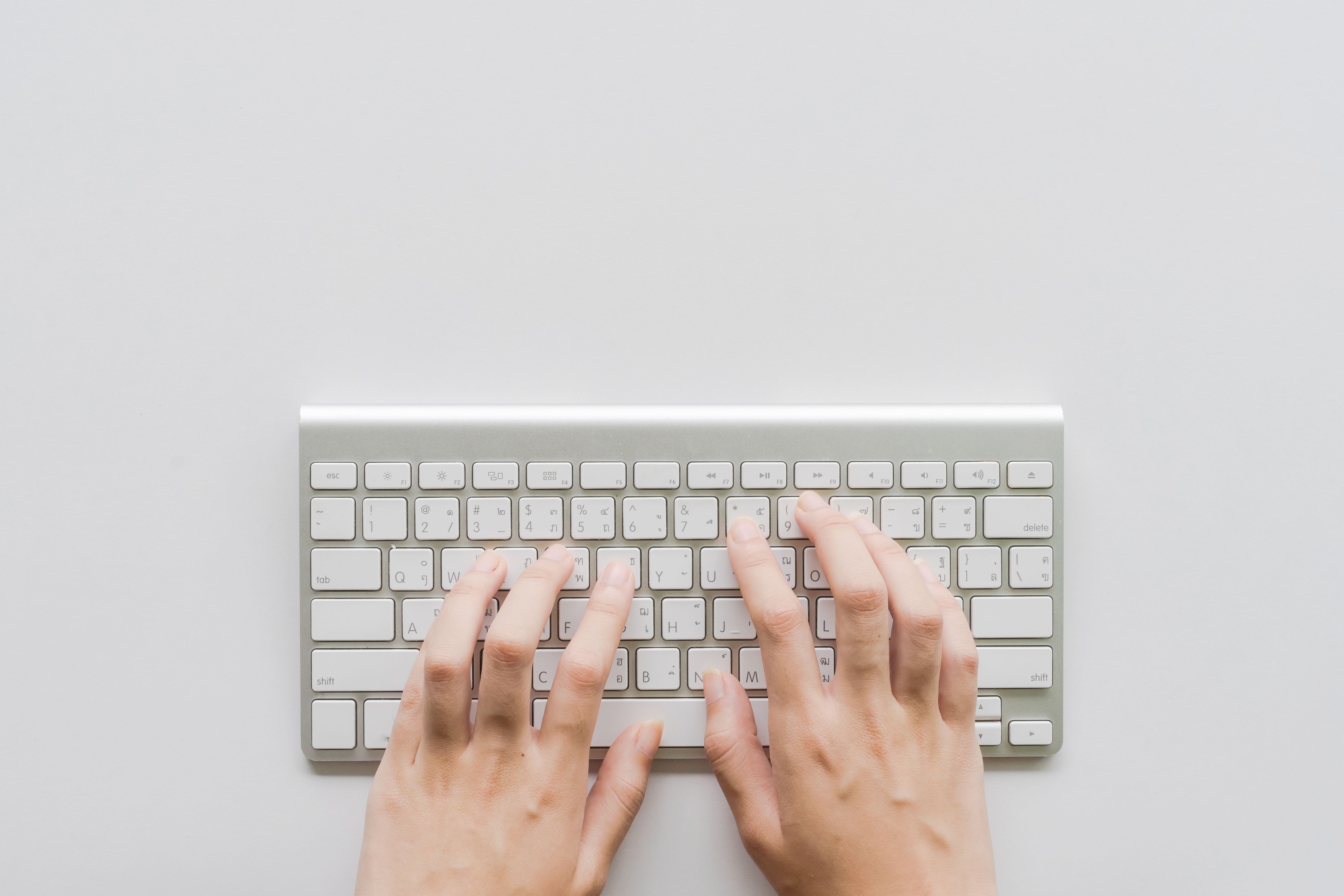Přímo nad záběrem rukou člověka na klávesnici malého počítače