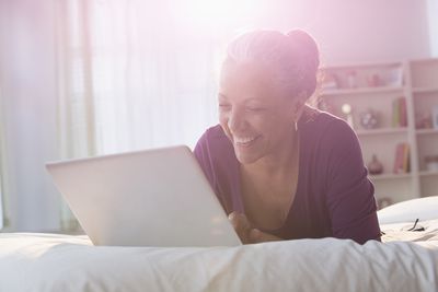 Žena pomocí přenosného počítače na posteli