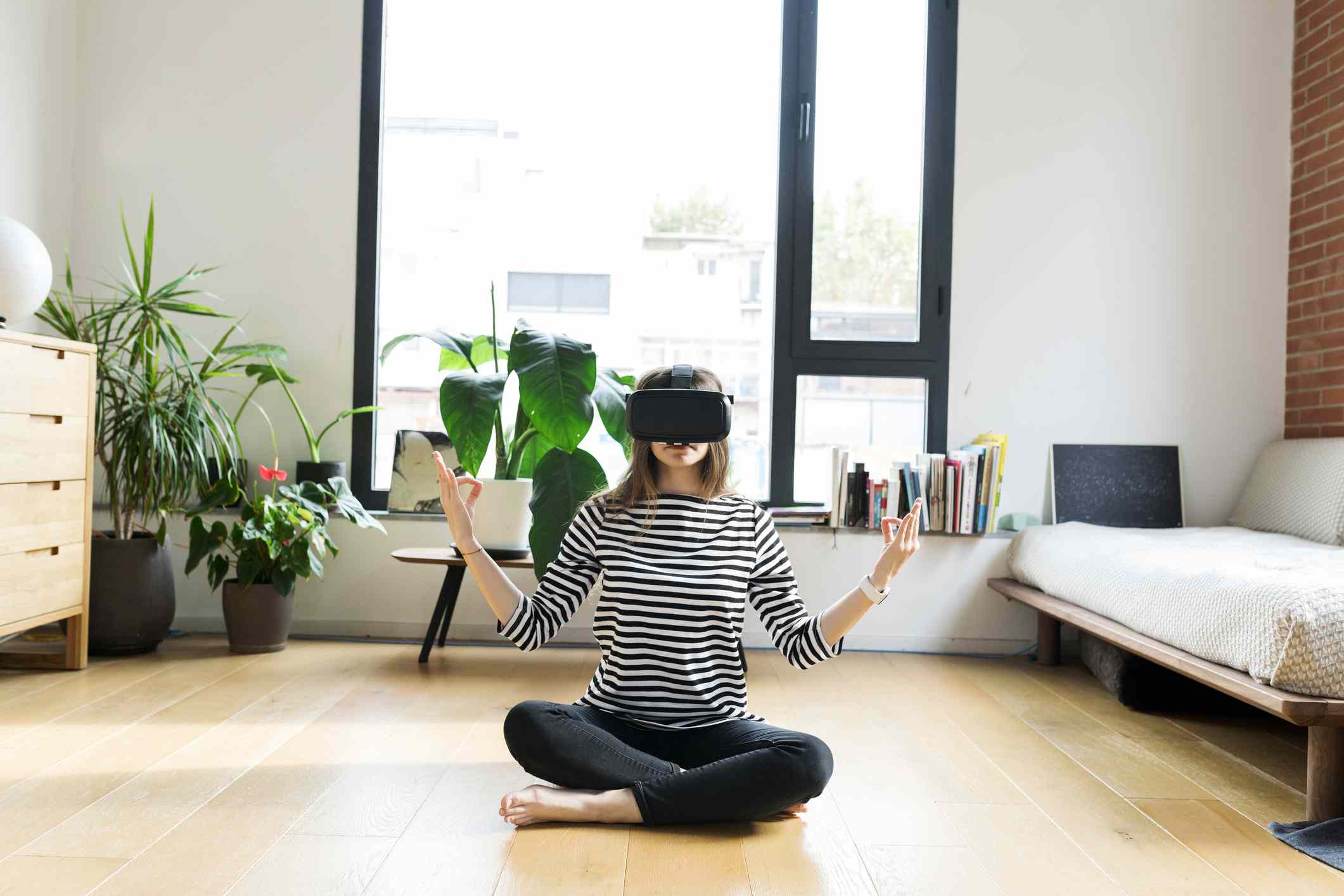 Mladý člověk doma nosí brýle VR a dělá jógu.