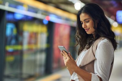 Mladá žena s smartphone na nástupišti vlaku