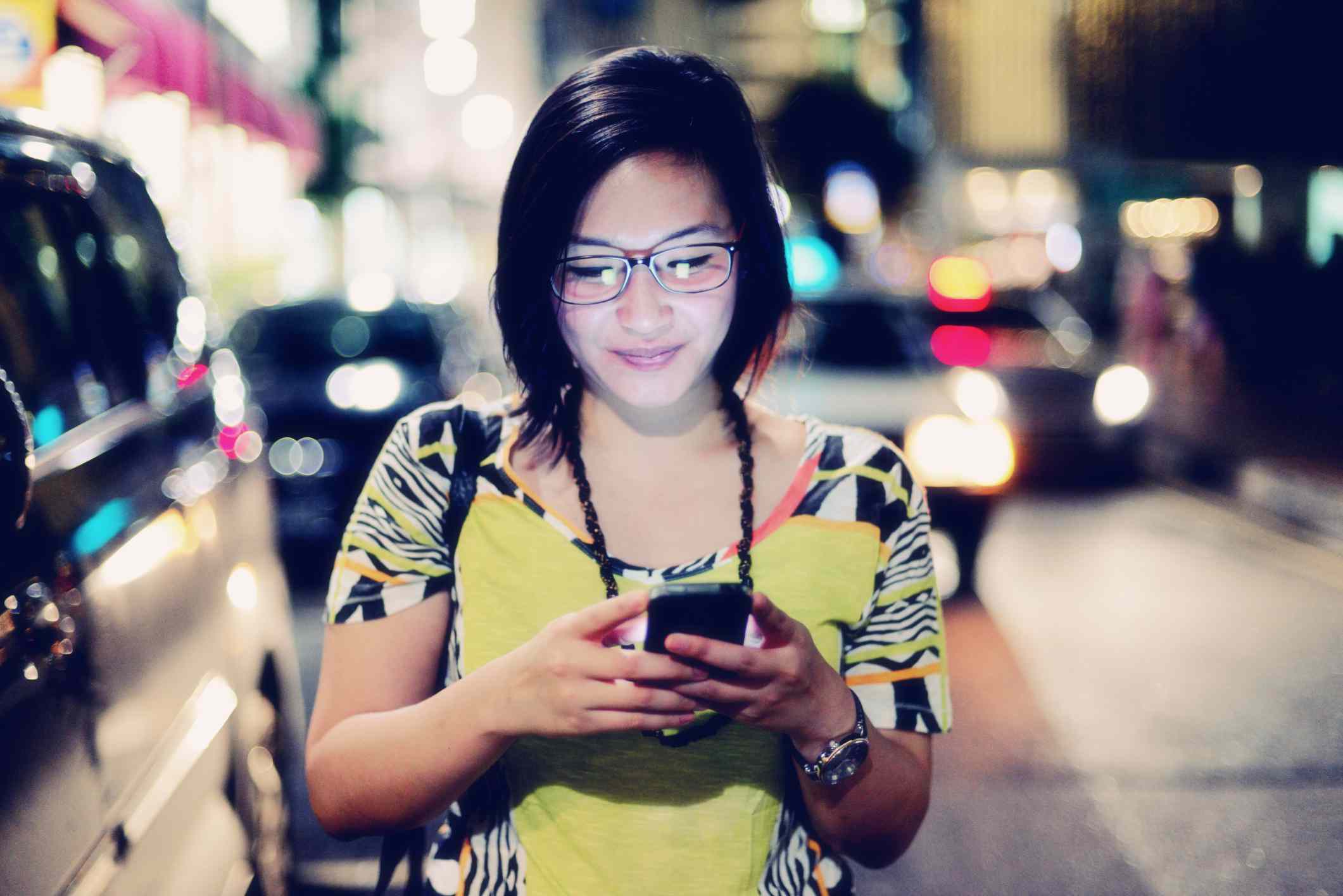 Typy pro chodce na smartphonu na městské ulici v noci